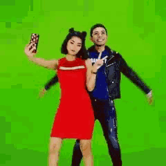 a man and a woman are posing for a selfie on a green screen