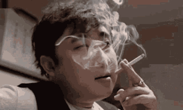 a man is smoking a cigarette in a dark room .