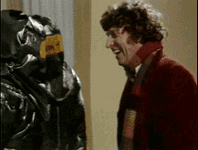 a man in a red sweater is smiling next to a man in a black helmet