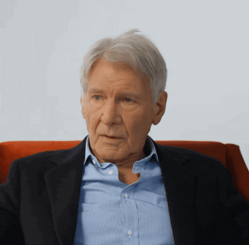 a man with gray hair and a blue shirt is wearing a black jacket
