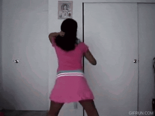 a woman in a pink dress is dancing in front of a white door in a room .
