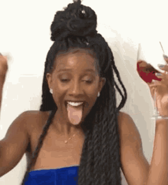 a woman is holding a glass of wine and sticking out her tongue .