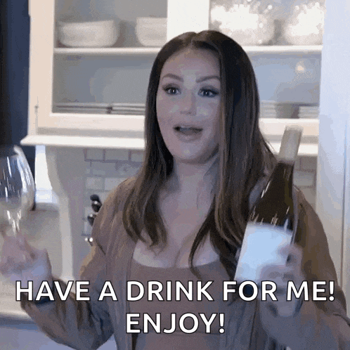 a woman is holding a bottle of wine and a glass of wine and says have a drink for me enjoy !