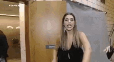 a woman in a black dress is standing in front of a door in a room .