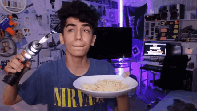 a boy wearing a nirvana shirt is holding a bowl of food