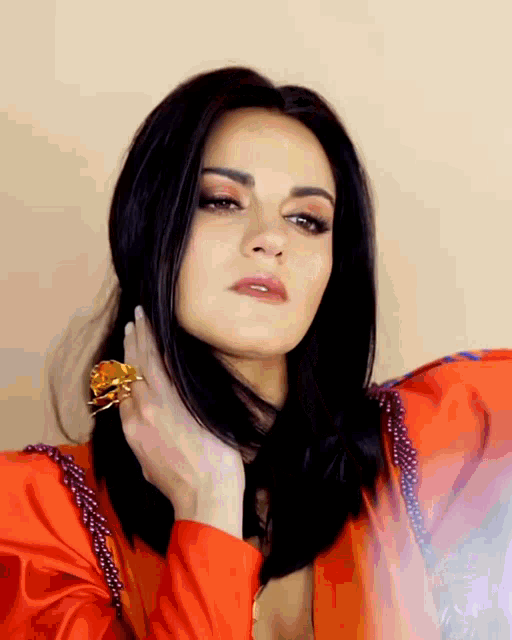 a woman wearing an orange jacket and a gold ring