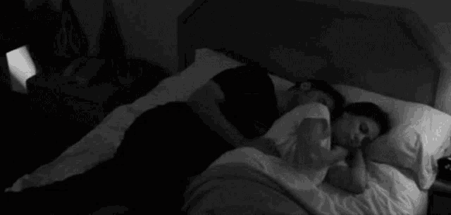 a man and a woman are sleeping in a bed .