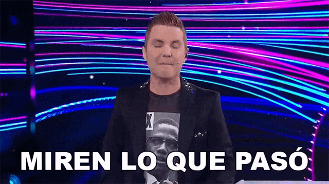 a man in a suit is making a funny face in front of a colorful background and the words miren lo que paso .