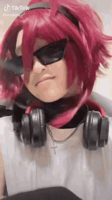 a person wearing a red wig , headphones , sunglasses and a cross necklace .