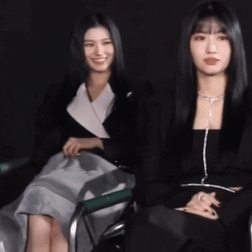 two women are sitting next to each other in a chair .