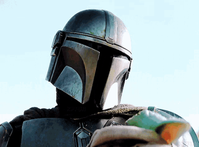 a close up of a person wearing a helmet and holding a baby with the letters kfbn on the bottom