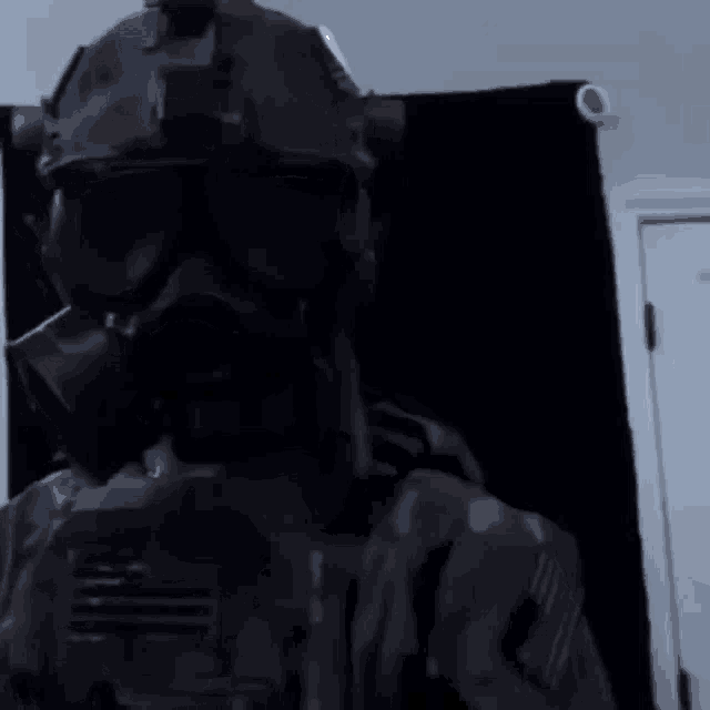 a man wearing a gas mask and helmet is standing in a dark room .