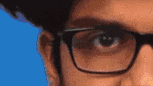 a close up of a man 's eye with glasses on