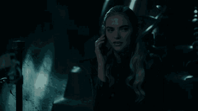 a woman in a dark room talking on a cell phone