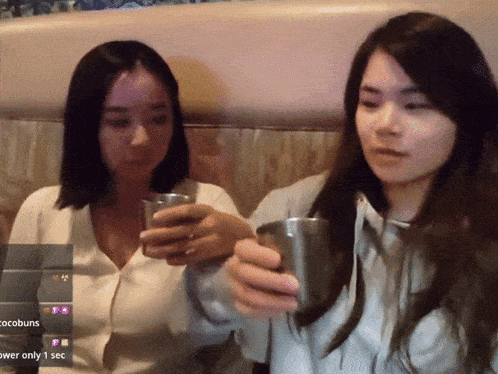 two women are holding cups in front of a screen that says cocobuns on it