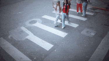 a group of people are crossing a street with a key painted on the sidewalk