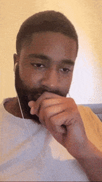 a man with a beard is wearing earbuds and covering his mouth