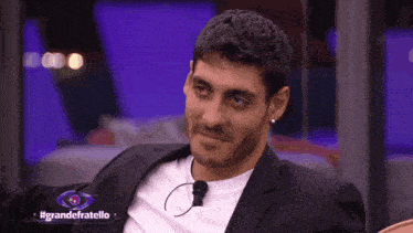 a man sitting in front of a sign that says grandefratello on it
