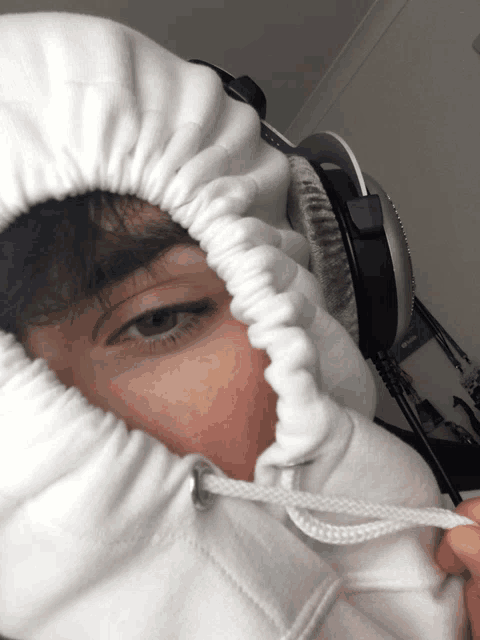 a person wearing headphones and a white hoodie covering their face