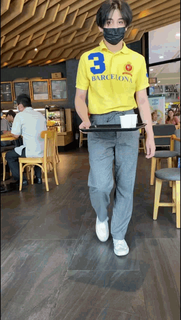 a man wearing a yellow shirt with the number 3 on it is carrying a tray
