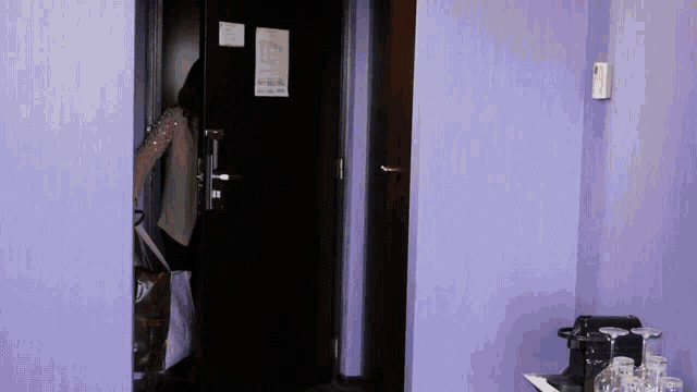 a room with purple walls and a black door has a sign on the door that says " no smoking "