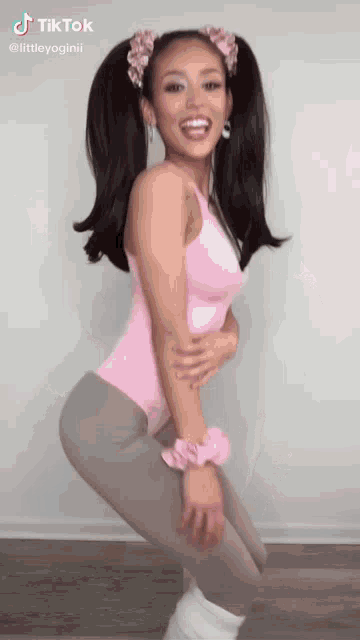 a woman in a pink leotard and gray leggings is dancing .