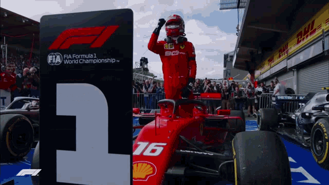 a man in a red ferrari race car stands in front of a sign that says fia formula 1 world championship