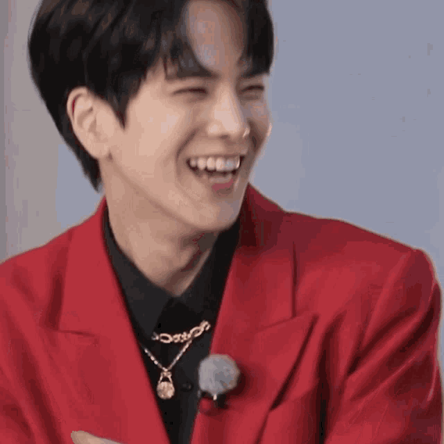 a young man wearing a red jacket and black shirt is smiling
