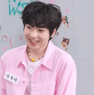 a young man is wearing a pink shirt and a necklace .