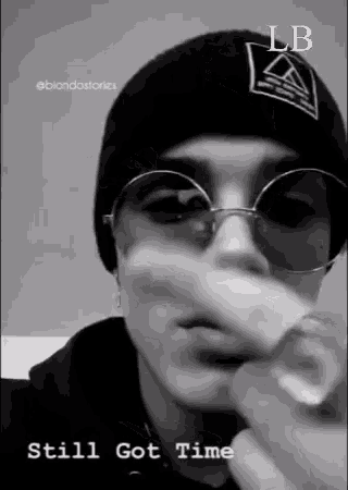 a black and white photo of a person wearing sunglasses and a beanie ..