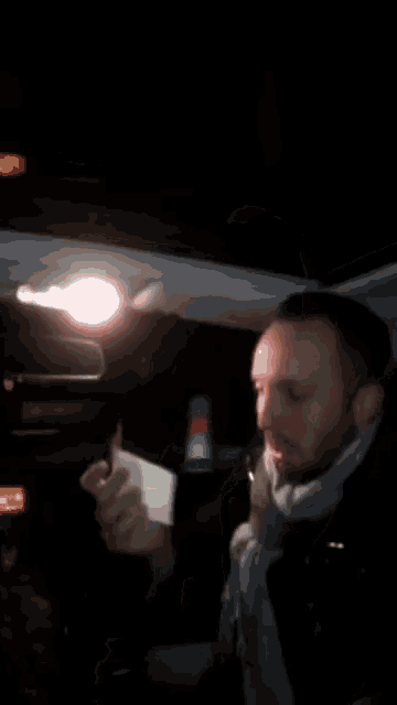 a man is holding a piece of paper in his hands in a dark room