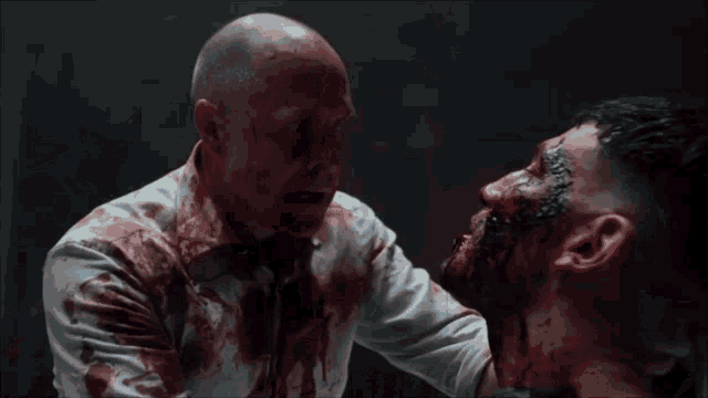 two men are fighting each other with blood on their faces .