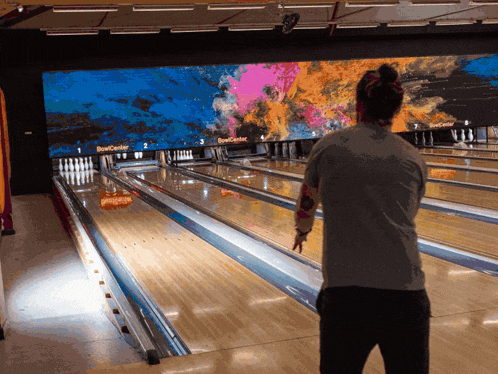 a woman stands in front of a bowling alley that says bowl center on the wall
