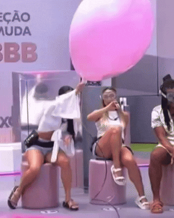 a woman is blowing up a large pink balloon in front of a sign that says bb