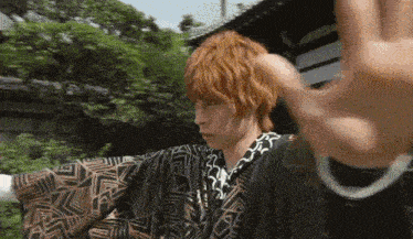 a man with red hair is wearing a kimono and a black shirt