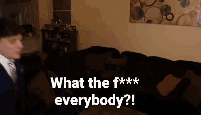 a man standing in front of a couch with the words what the f *** everybody written on it