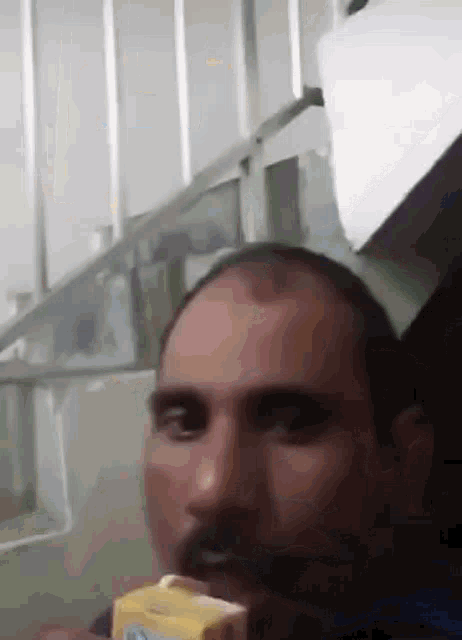 a man with a mustache is holding a carton of milk in his hand .