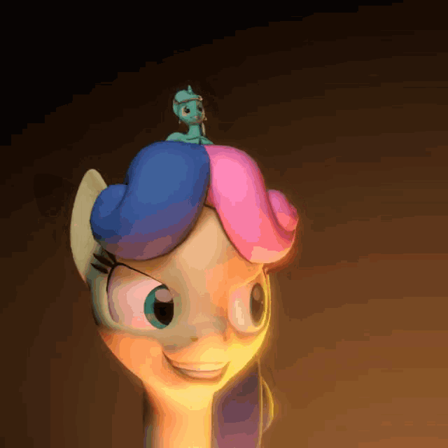 a cartoon pony with a blue and pink mane has a toy on its head