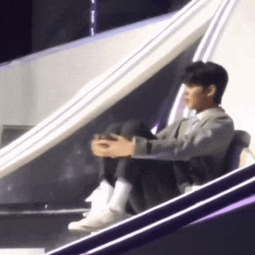a man is sitting on a stage holding a video game controller