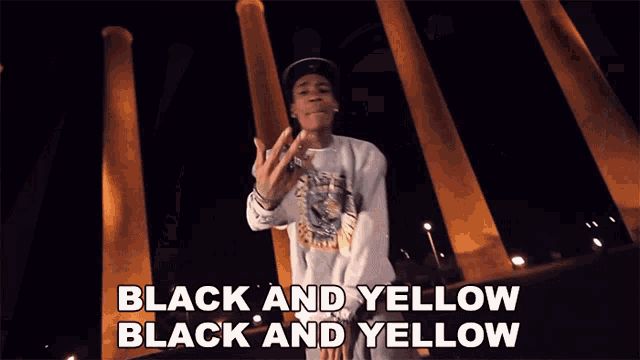 a man stands in front of a row of columns and says " black and yellow black and yellow "