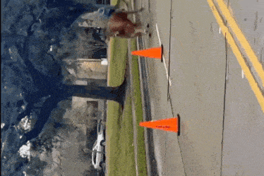 a person riding a bike on a sidewalk with a few orange cones