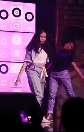 two girls are dancing on a stage in front of a sign that says ' i am a superhero '