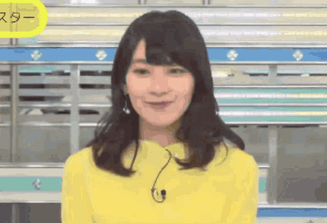 a woman wearing a yellow sweater with a microphone on her neck