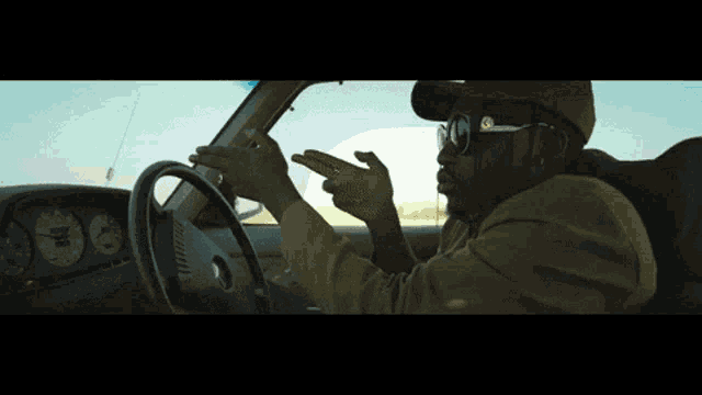 a man wearing sunglasses is driving a car