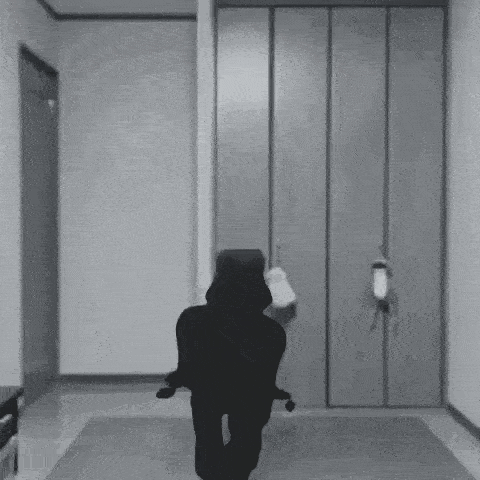 a black and white photo of a person standing in a room with a cat .