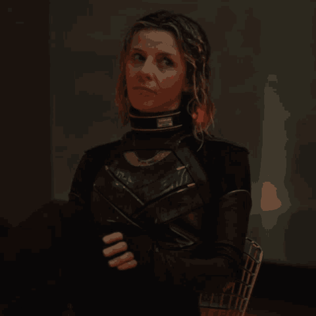 a woman sitting in a chair with her hands folded and a collar that says marvel on it