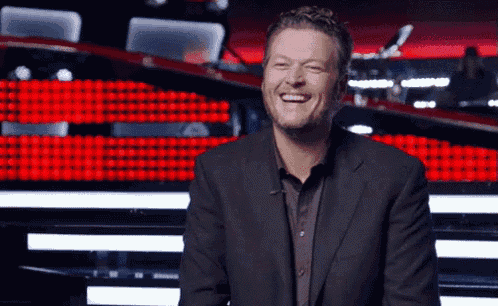 a man in a suit is smiling while sitting in front of a stage