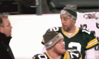 two green bay packers players are talking to a man