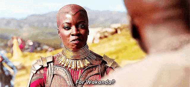 a woman is talking to a man in a field while wearing a necklace and armor .