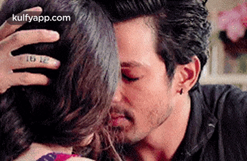 a man is kissing a woman on the forehead while holding her hair .